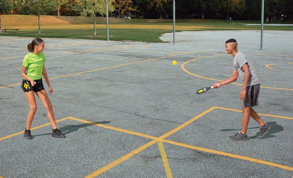 Students playing Street Racket outdoors on a court marked with tape
