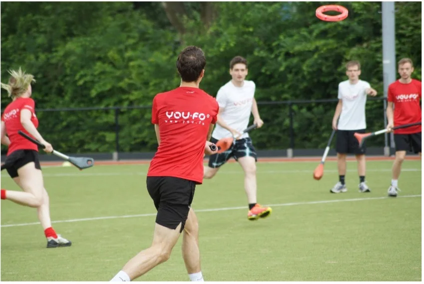 Students playing YOU.FO with aerodynamic rings and launching sticks in a gymnasium